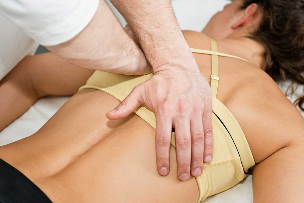 Pregnant person receiving a gentle chiropractic adjustment on a supportive table in a brightly lit clinic.