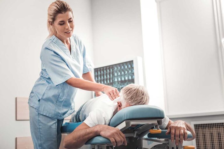 A chiropractor discusses spine models with a patient during a relaxed consultation in an exam room.